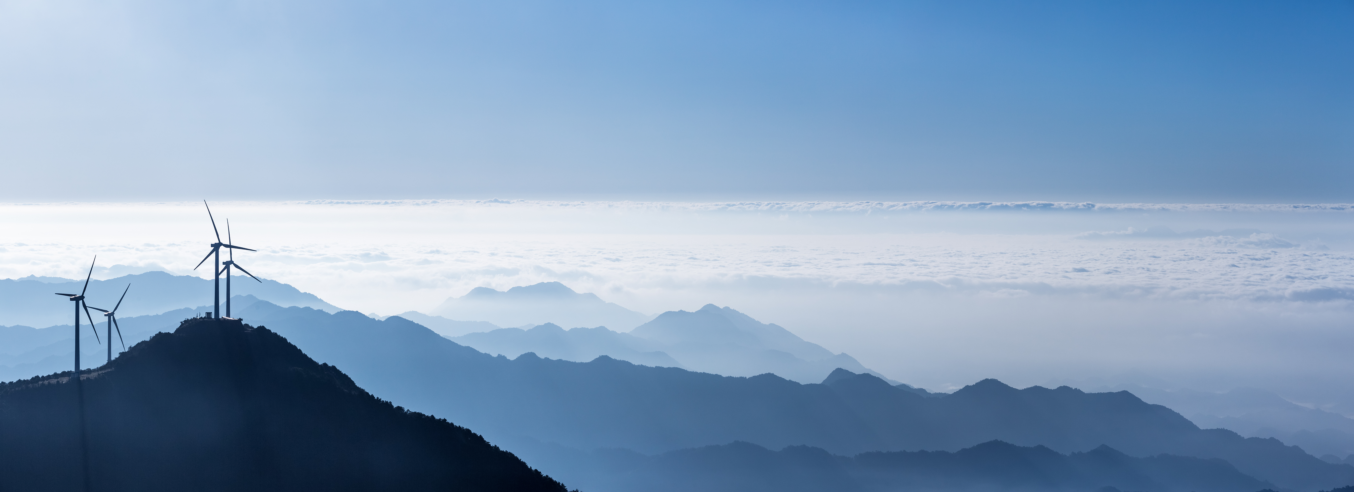 Image of wind farm propellors amidst clouds on a skyline
